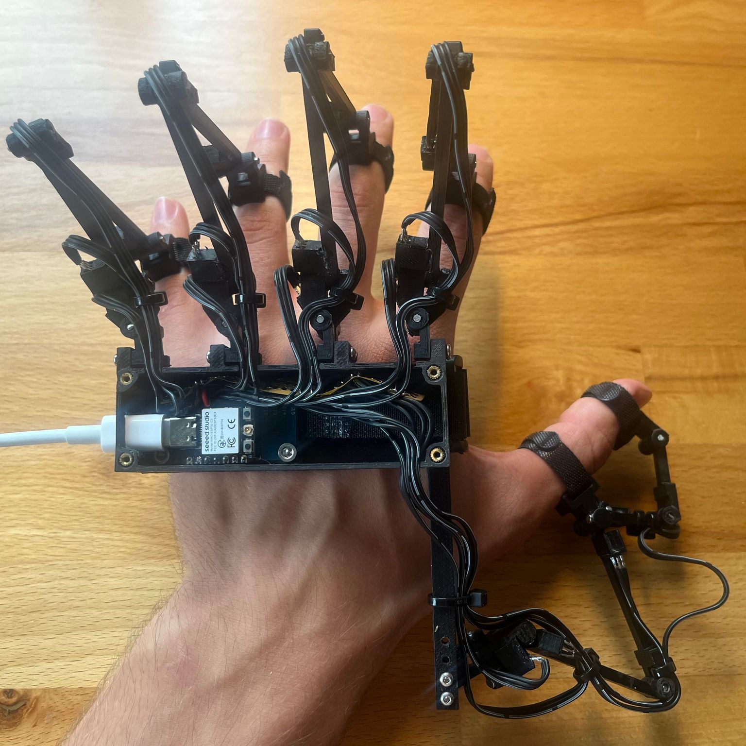 Max wearing the finger tracker glove, with articulated tracking links and wiring attached to the back of his hand